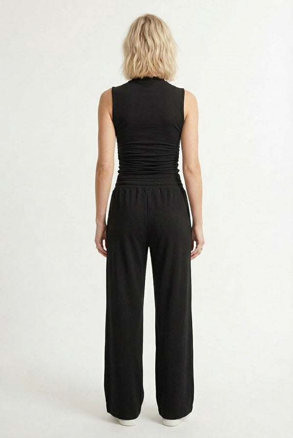 Woman wearing a classic onyx black sleeveless jumpsuit with a wide-leg silhouette.