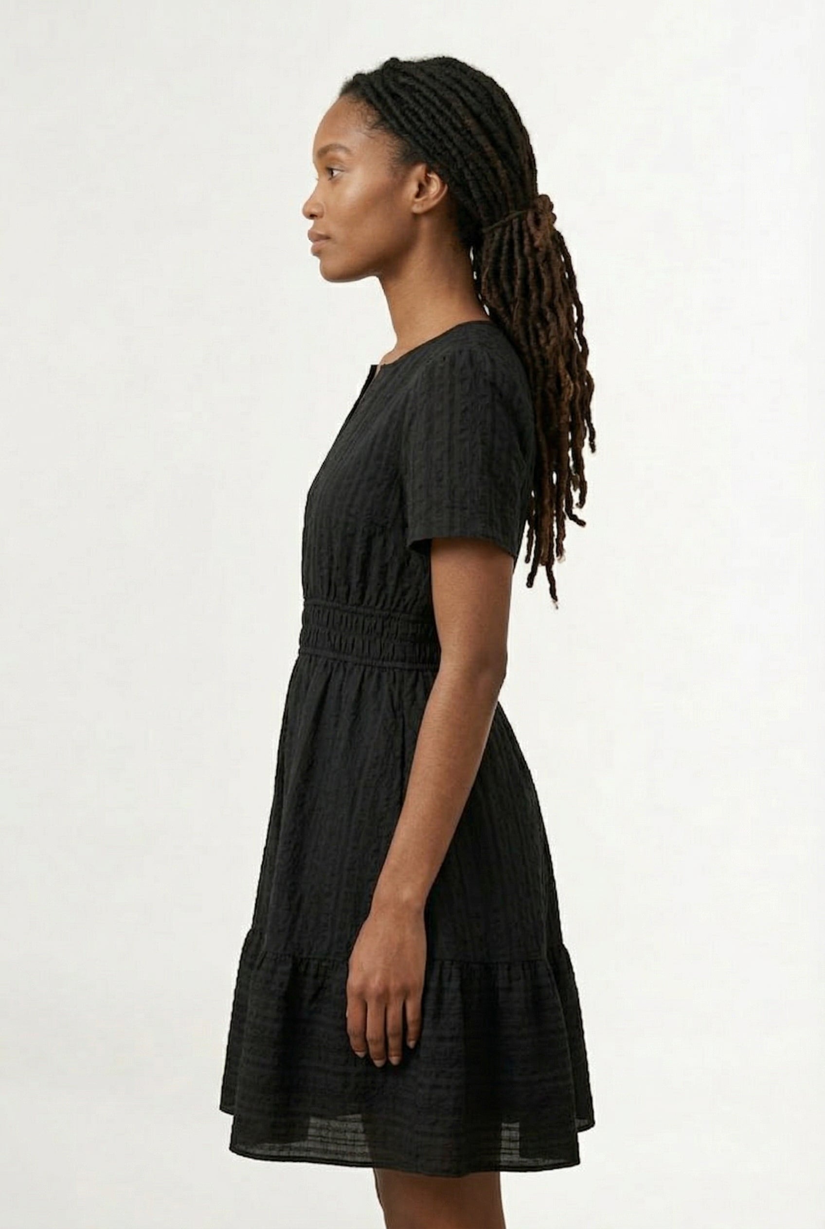 Woman wearing a short sleeve v-neck tiered dress in onyx black