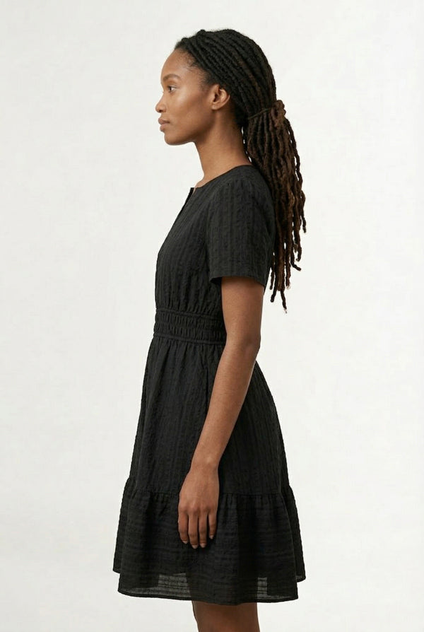 Woman wearing a short sleeve v-neck tiered dress in onyx black