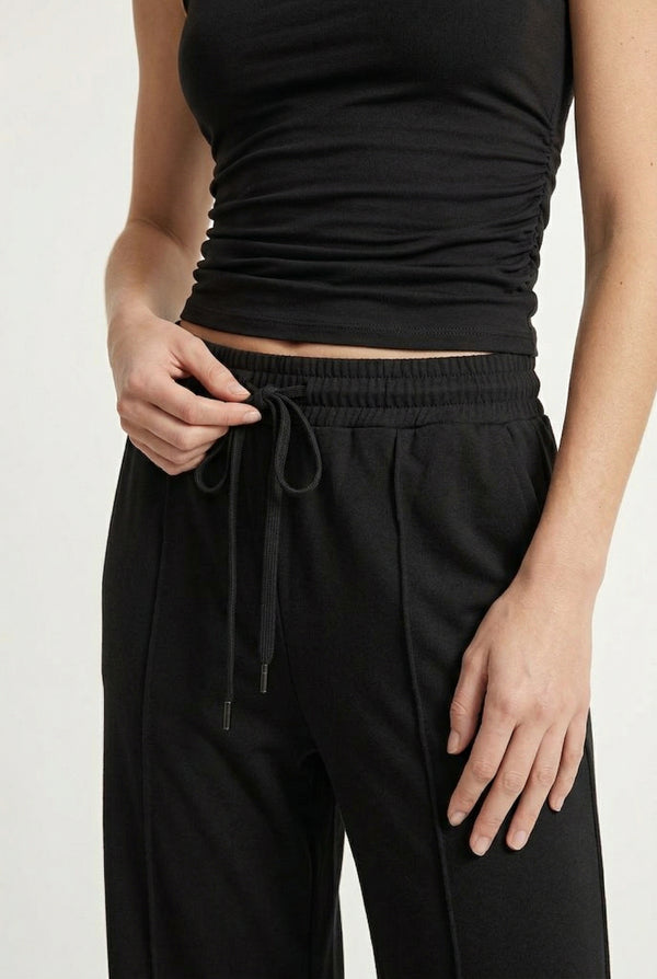 Woman wearing a classic onyx black sleeveless jumpsuit with a wide-leg silhouette.