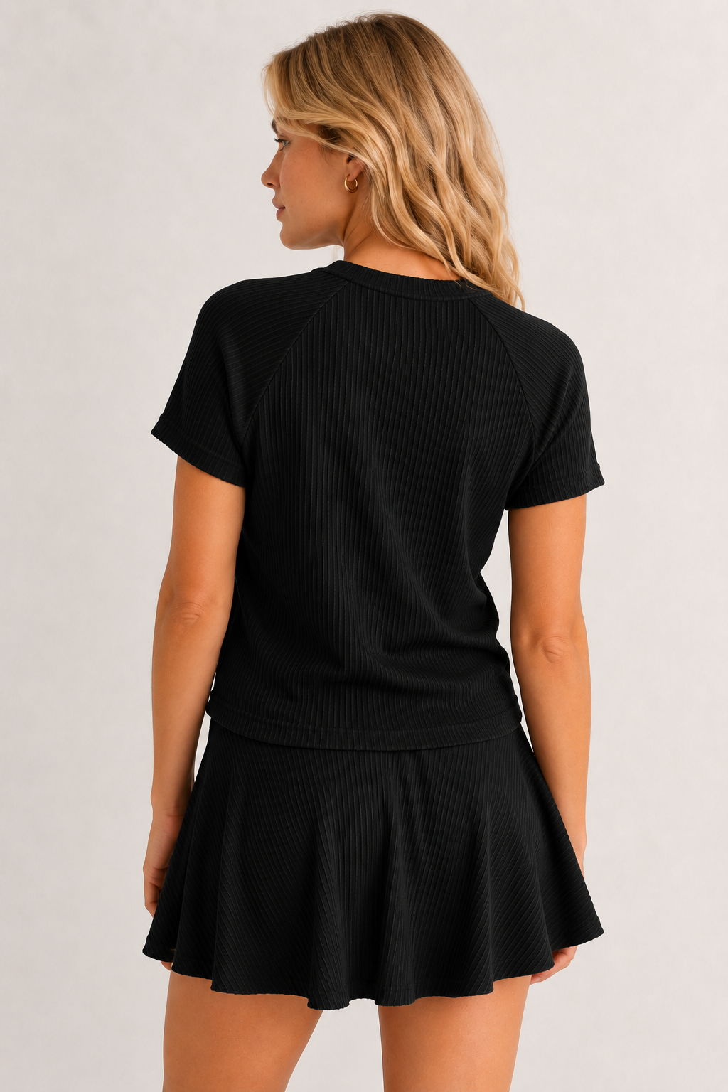 Woman wearing an onyx black short sleeve top and matching mini skirt lounge set.