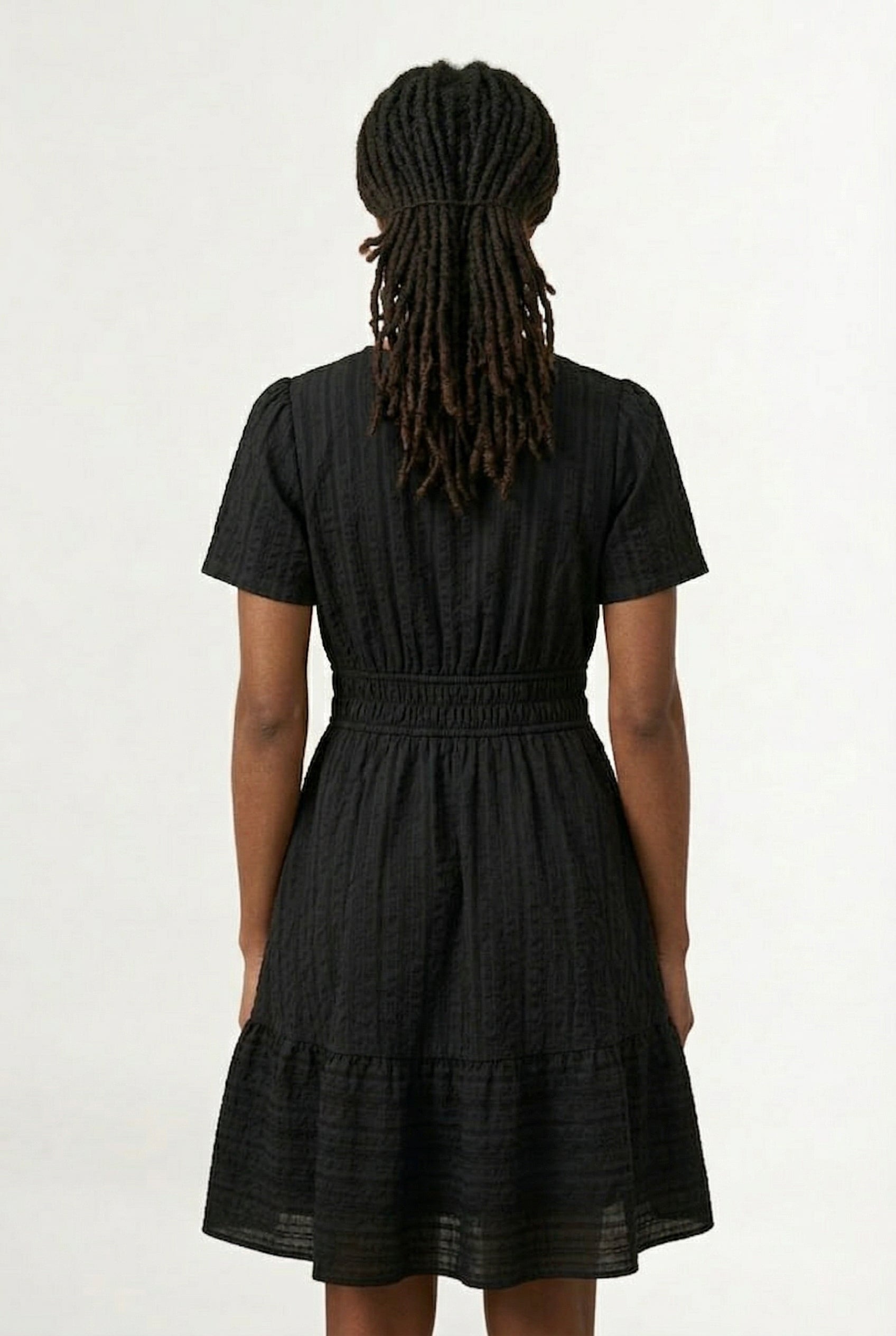 Woman wearing a short sleeve v-neck tiered dress in onyx black
