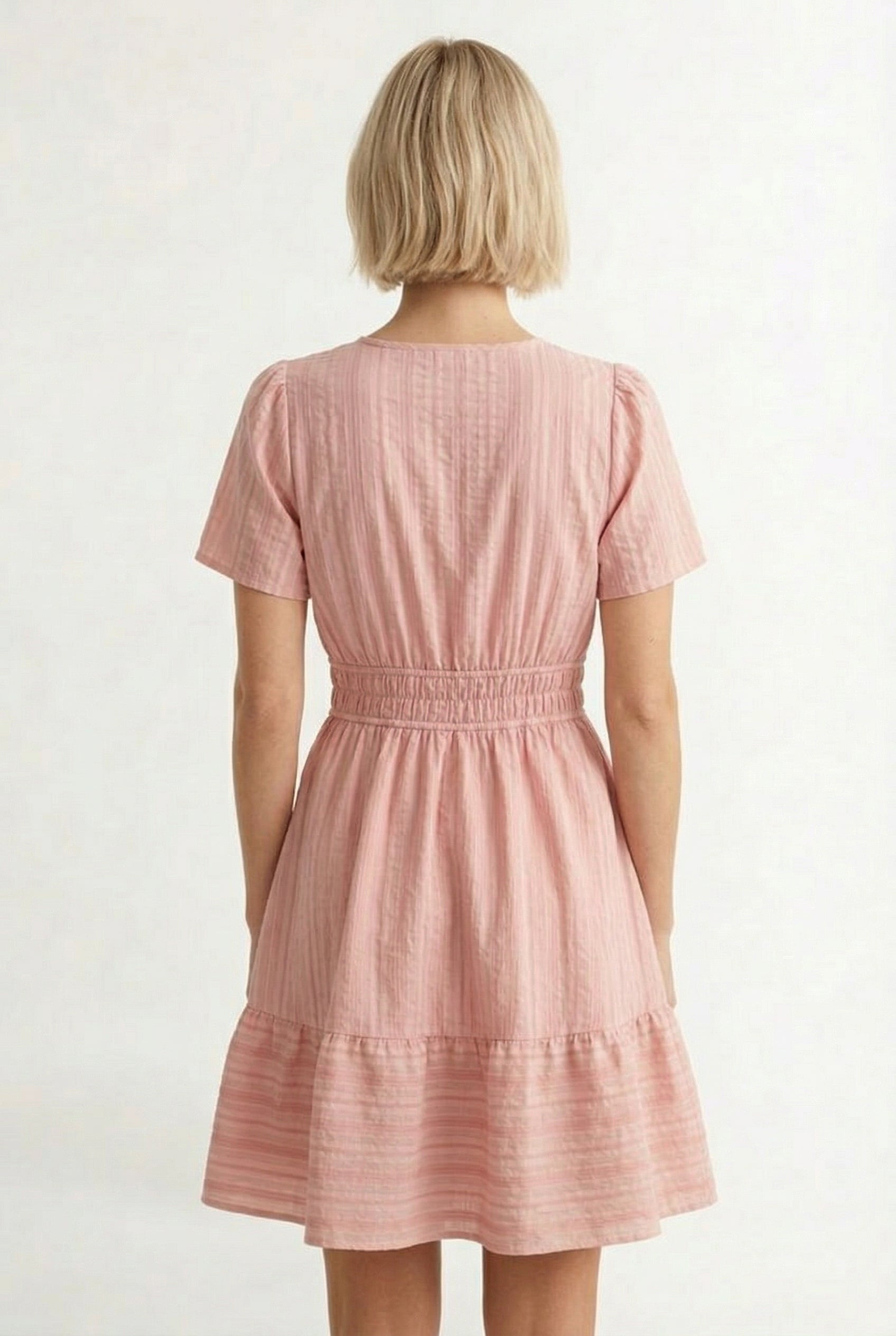 Woman wearing a short sleeve v-neck tiered dress in ash rose pink