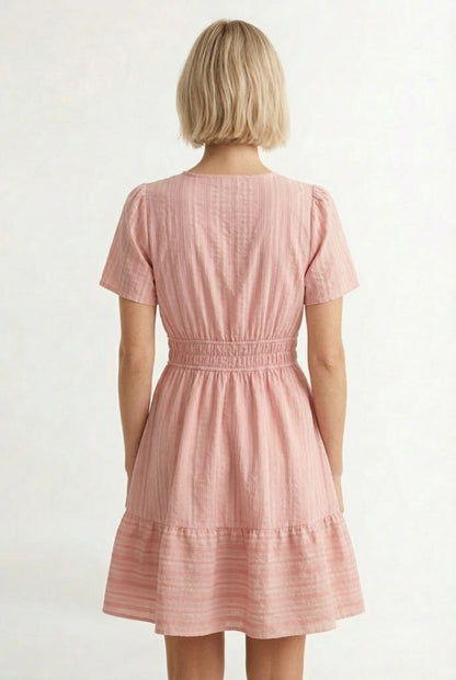 Woman wearing a short sleeve v-neck tiered dress in ash rose pink