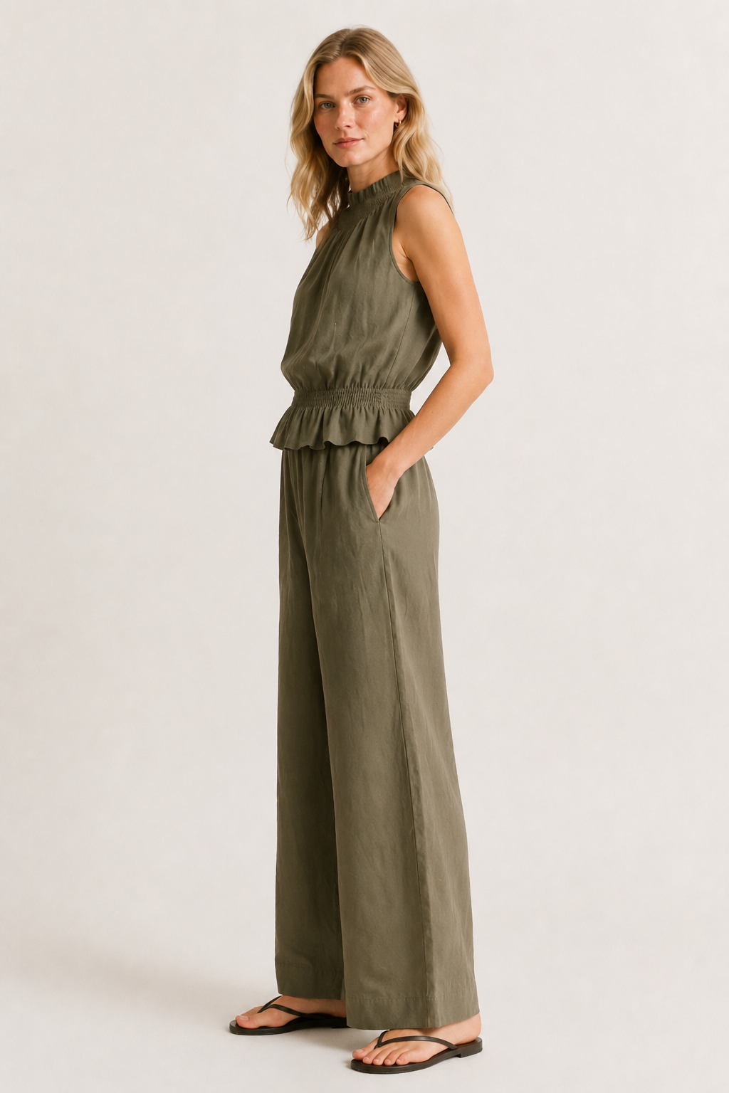 Woman wearing a premium minimalist cypress green two piece set with sleeveless top and wide leg pants