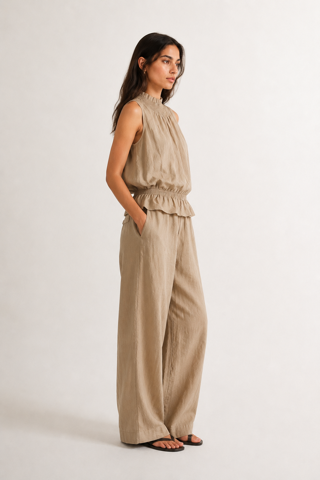 Woman wearing a premium minimalist dune beige two piece set with sleeveless top and wide leg pants