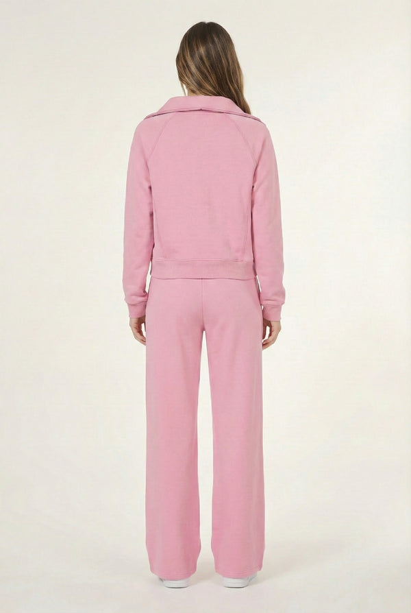 Woman wearing the LOHNR Élan Set in Rose Petal, featuring a smooth, sweatshirt-material half-zip pullover and matching structured pants.