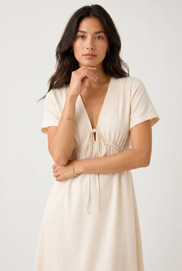 Model wearing the Sabine midi dress in light birch cream, front view studio shot.