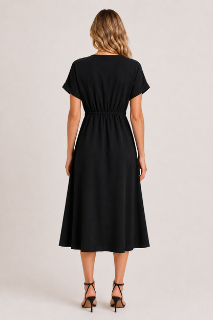 Model standing against a white studio background wearing the black onyx Sabine midi.