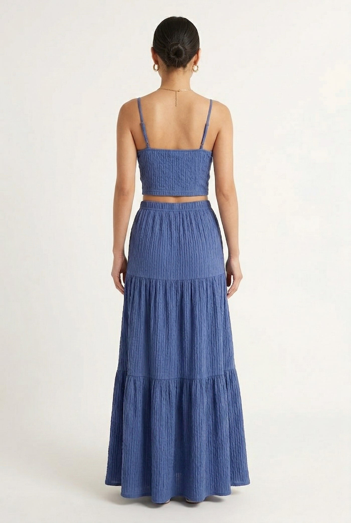 Woman modeling a Slate Blue two-piece matching set featuring a spaghetti strap crop top and tiered maxi skirt