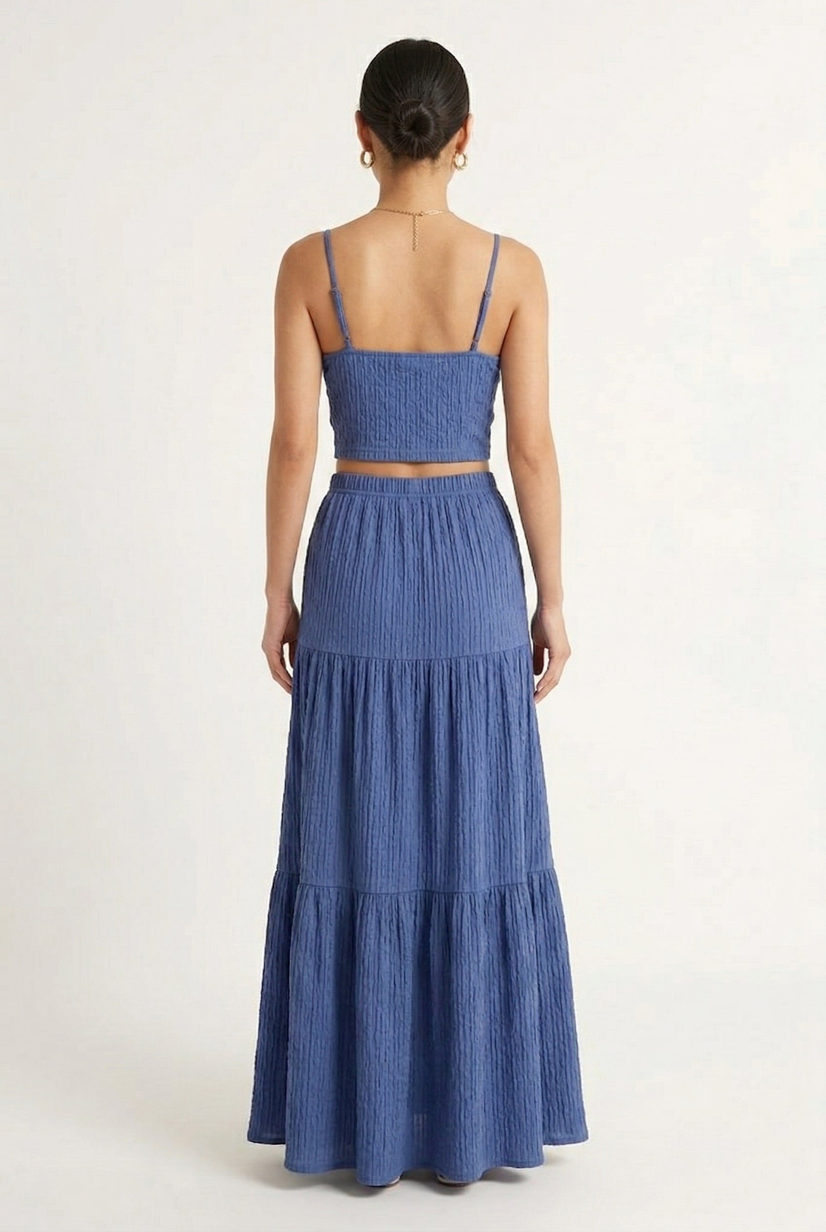 Woman modeling a Slate Blue two-piece matching set featuring a spaghetti strap crop top and tiered maxi skirt