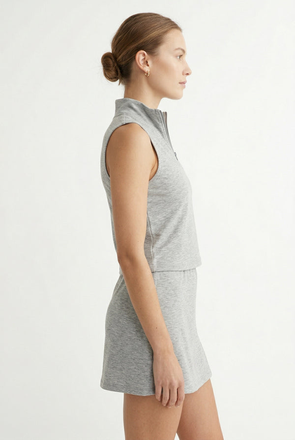 A woman wearing a Heather Light Gray sleeveless athletic dress with a zippered collar and matching skirt.