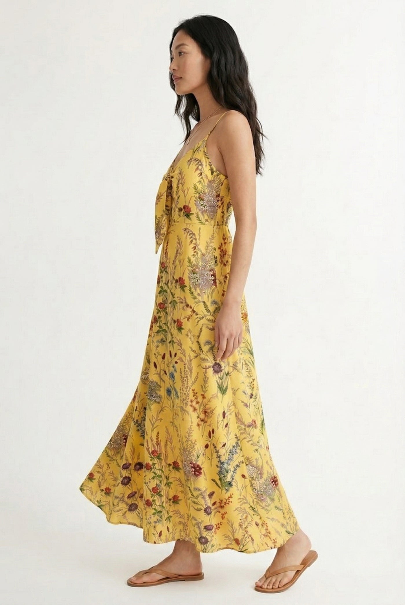 Woman wearing a soft honey yellow floral print maxi dress with spaghetti straps