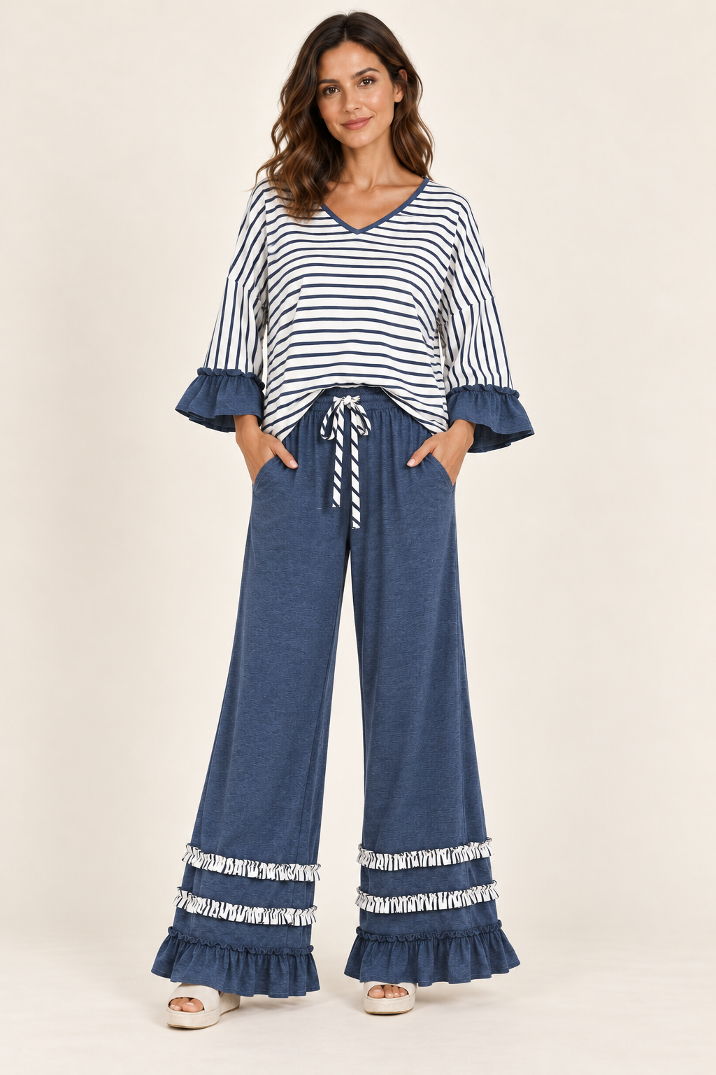 Woman wearing the Tess striped V-neck top and ruffle-hem pants in Blue, front view. #3F4B64