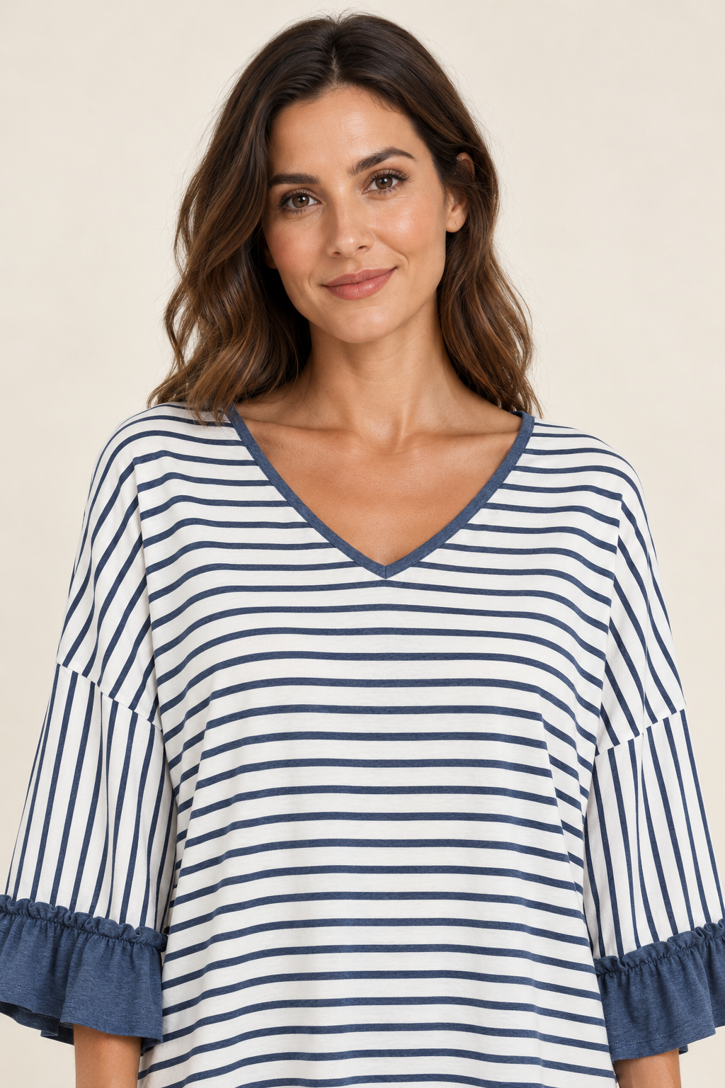 Close-up portrait of a woman wearing the Tess striped top in Blue, showing the V-neckline and ruffled sleeves.