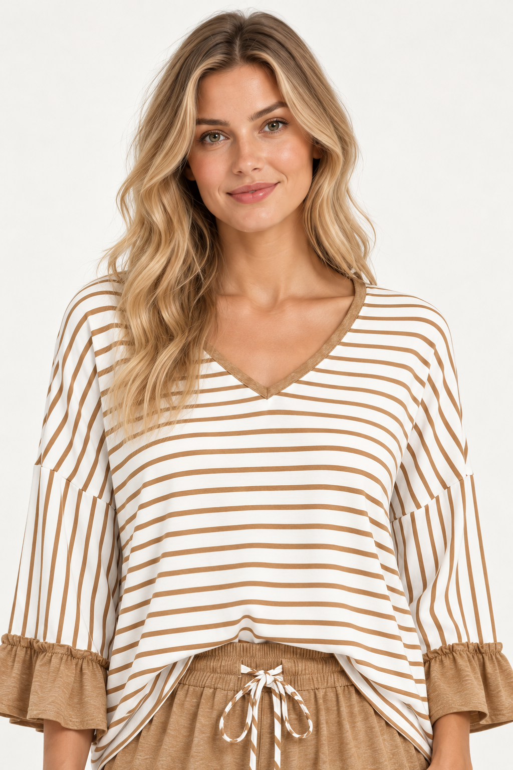 Close-up portrait of a woman wearing the Tess striped top in Camel, showing the V-neckline and ruffled sleeves.