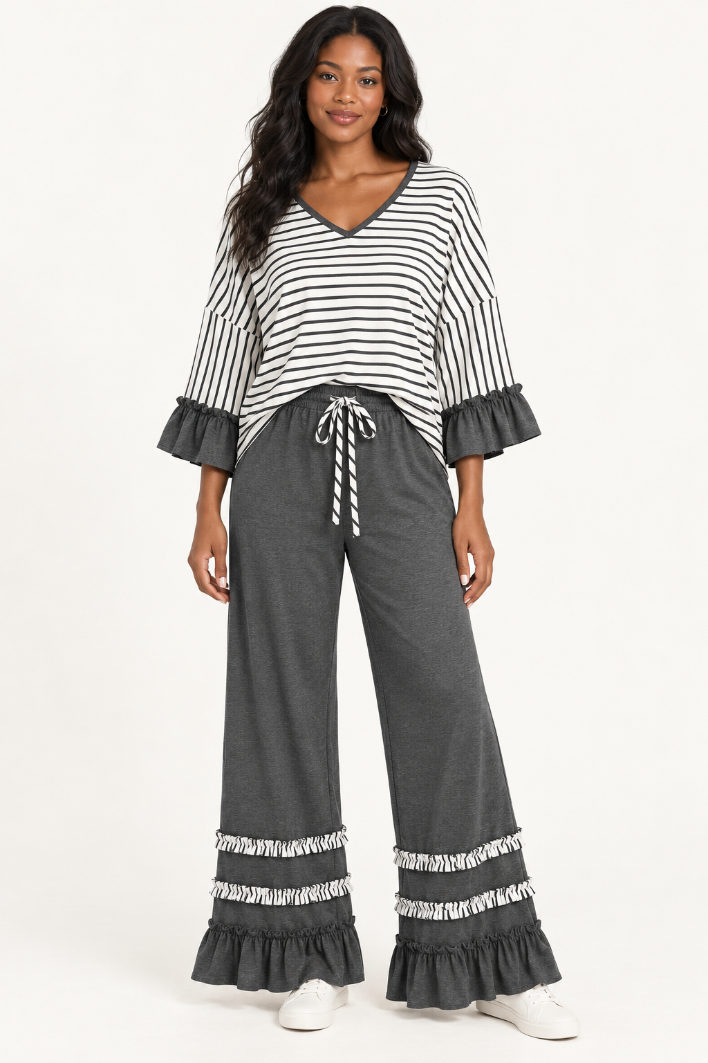 Woman wearing the Tess striped V-neck top and ruffle-hem pants in Charcoal, front view. #53595B