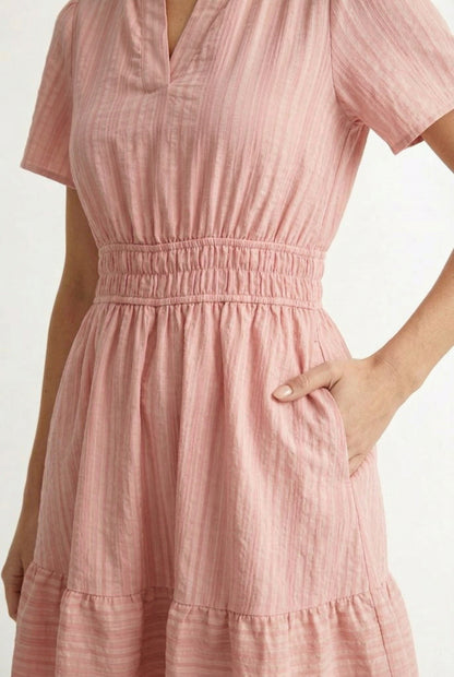 Woman wearing a short sleeve v-neck tiered dress in ash rose pink