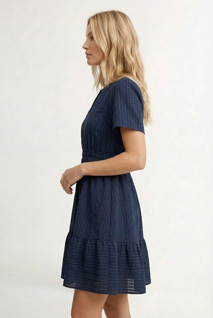 Woman wearing a short sleeve v-neck tiered dress in total eclipse navy blue