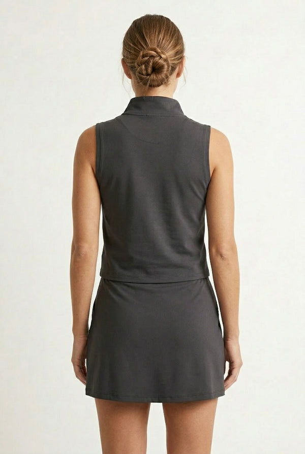 A woman wearing a sleek Black Eyeliner colored sleeveless athletic dress with a mock neck zipper.