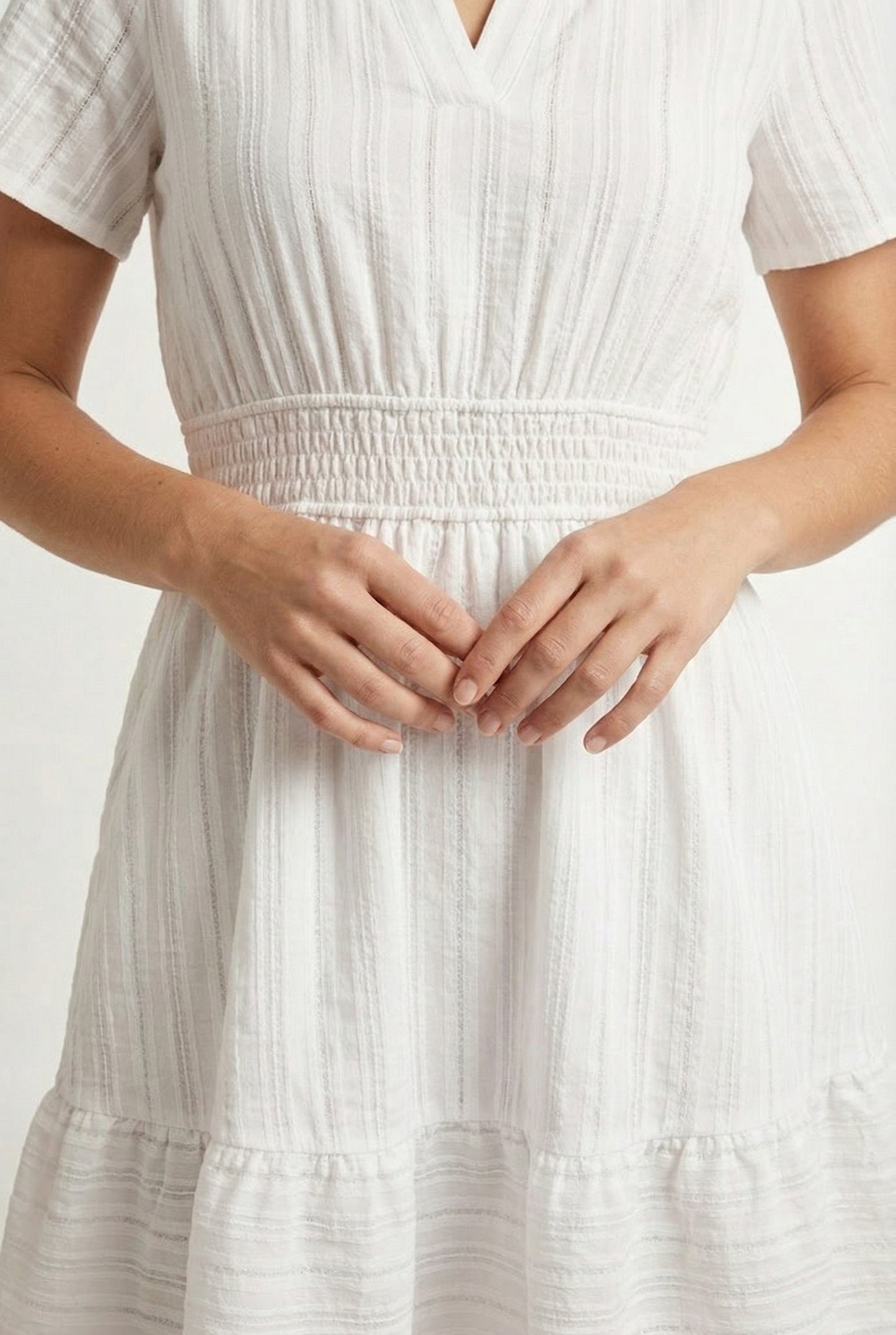 Woman wearing a short sleeve v-neck tiered dress in matte pearl white
