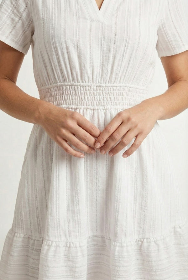 Woman wearing a short sleeve v-neck tiered dress in matte pearl white