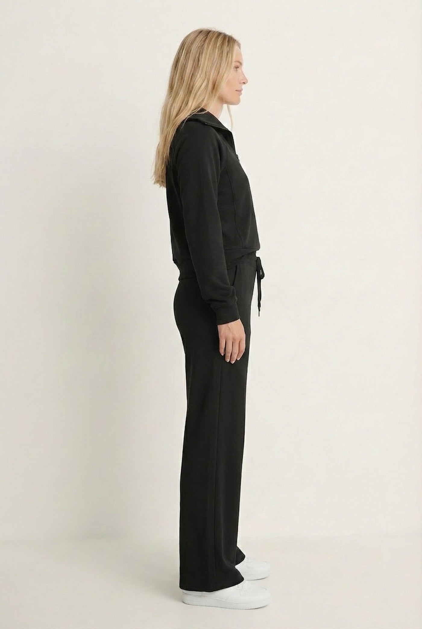 Woman wearing the LOHNR Élan Set in True Black, featuring a smooth, sweatshirt-material half-zip pullover and matching structured pants.