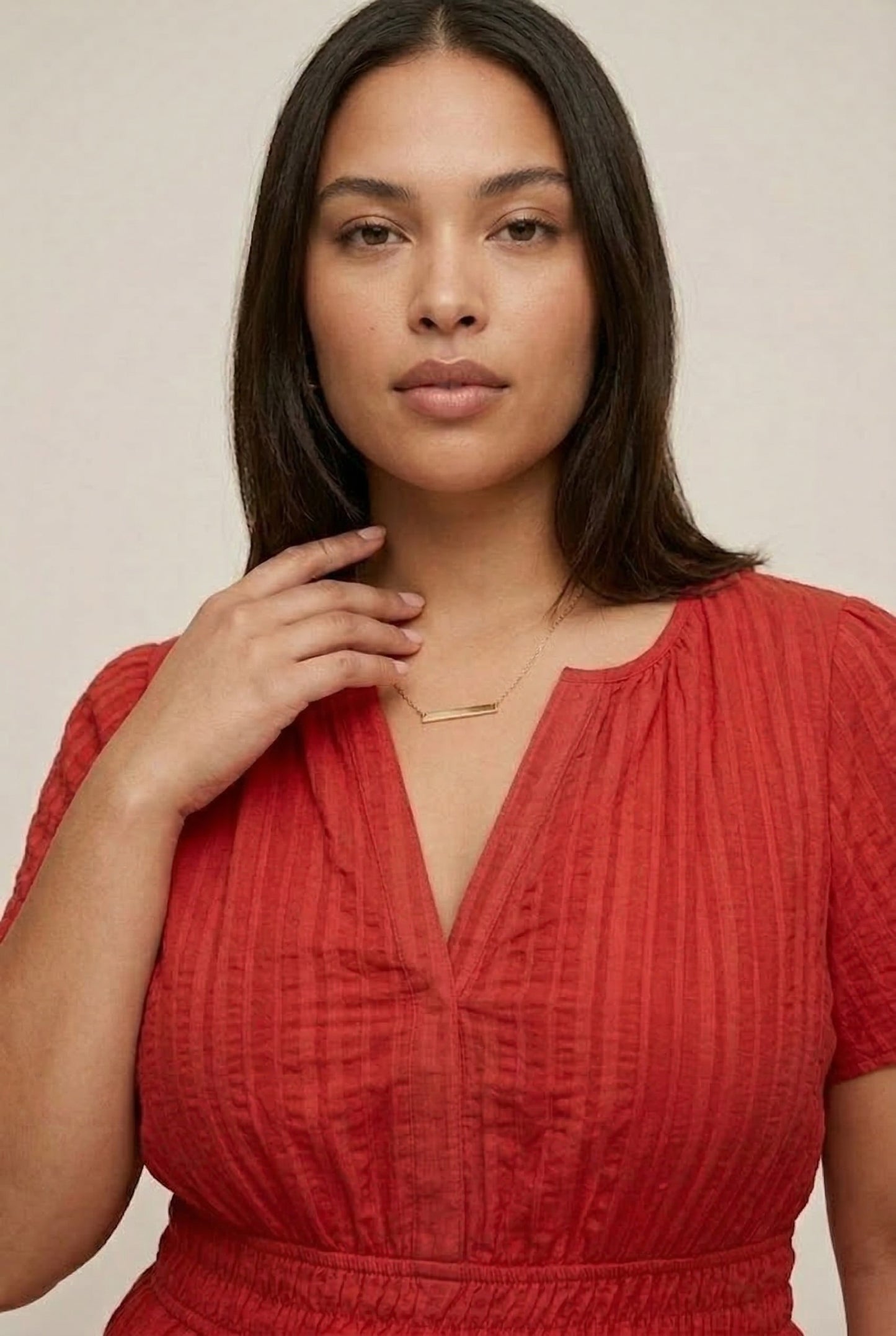 A woman modeling a Cinnabar red short-sleeve midi dress with a button-down front and tiered skirt.