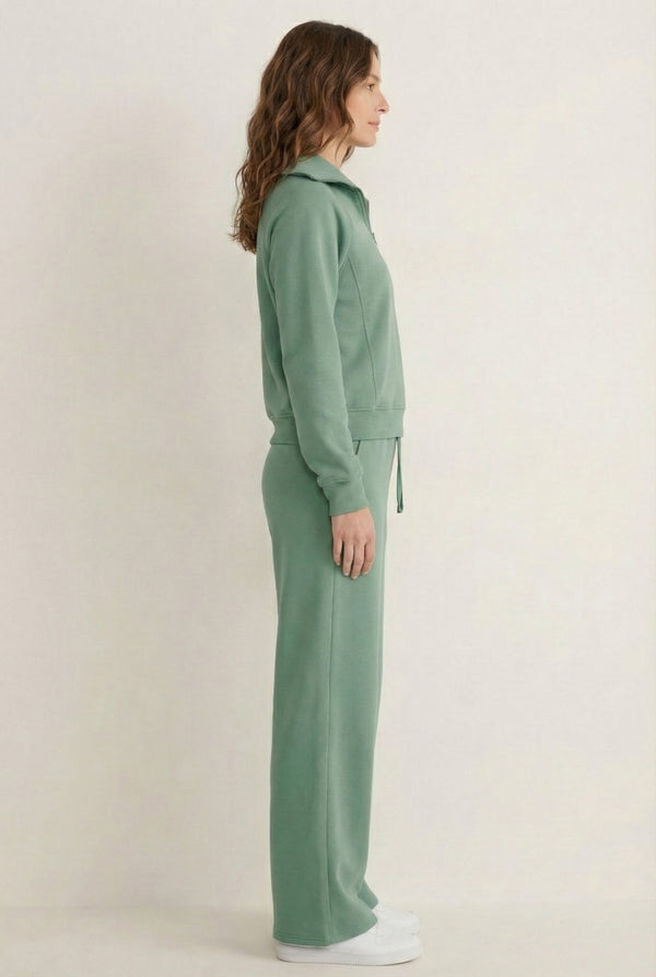 Woman wearing the LOHNR Élan Set in Eucalyptus, featuring a smooth, sweatshirt-material half-zip pullover and matching structured pants.