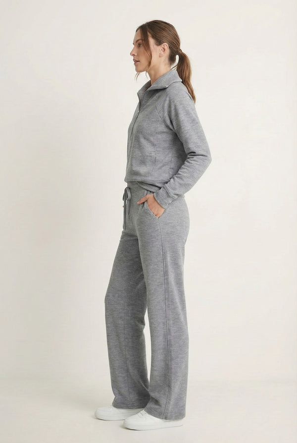 Woman wearing the LOHNR Élan Set in Heather Fog, featuring a smooth, sweatshirt-material half-zip pullover and matching structured pants.