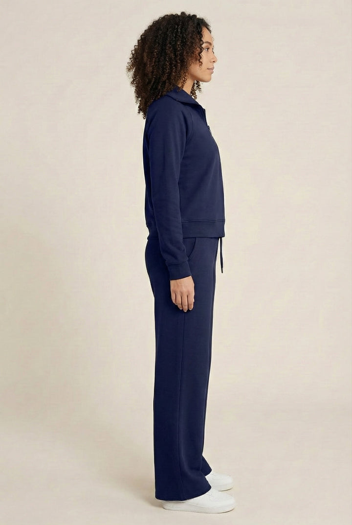 Woman wearing the LOHNR Élan Set in Midnight Navy, featuring a smooth, sweatshirt-material half-zip pullover and matching structured pants.