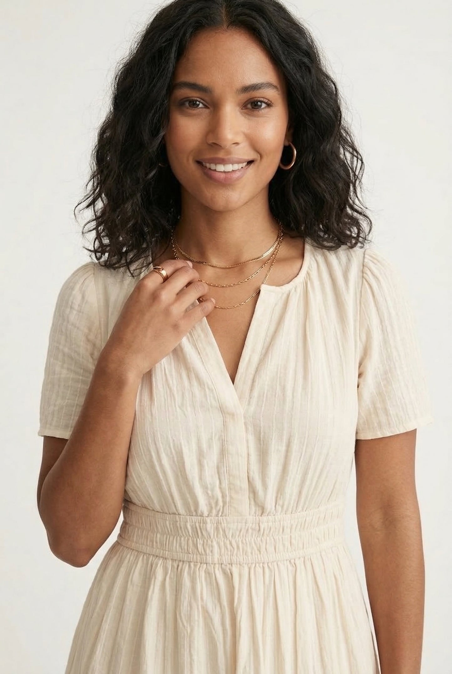 A woman posing in an Oat beige short-sleeve midi dress featuring a button-down bodice and flowy skirt.