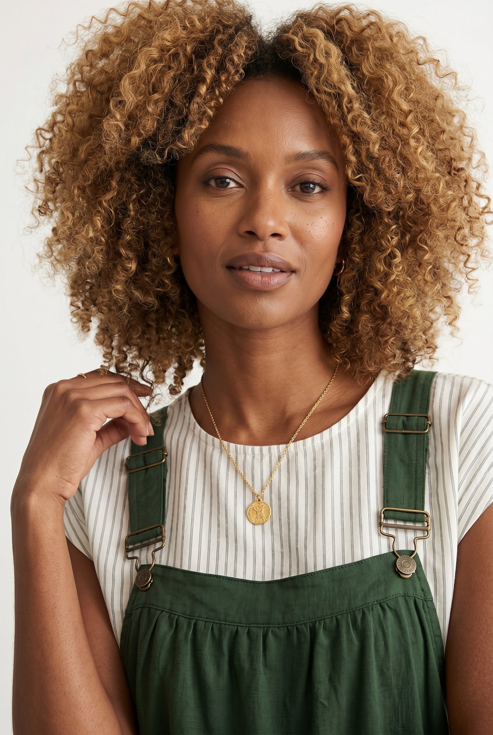 Woman wearing a scarab dark green midi-length pinafore dress layered over a white long-sleeve top