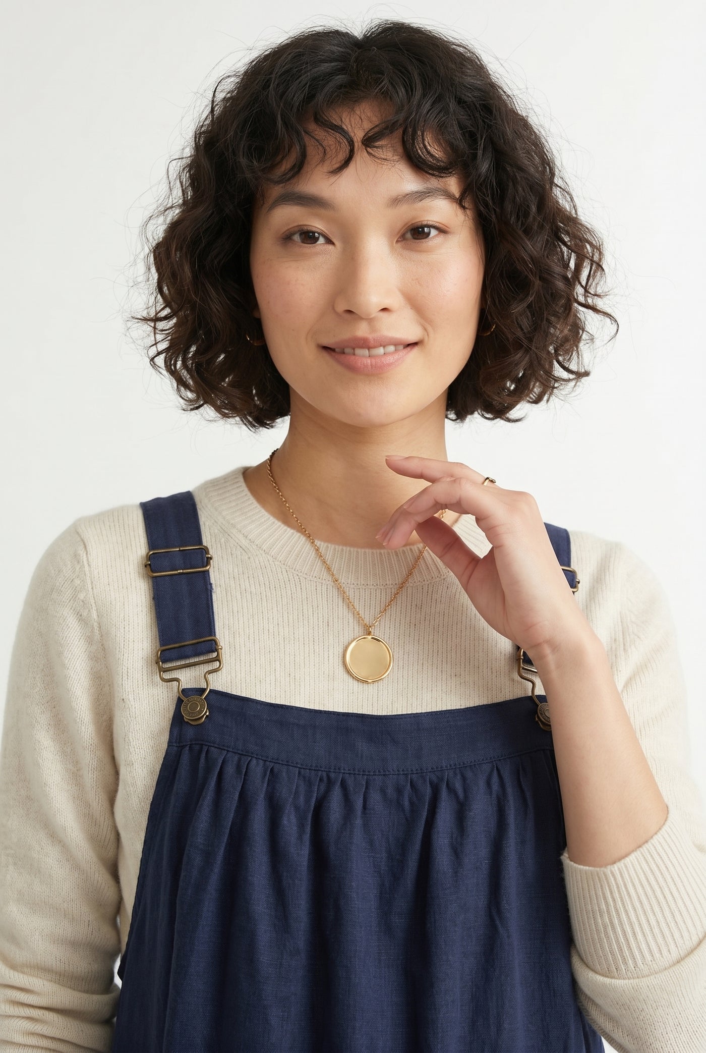 Woman wearing a total eclipse dark navy blue midi-length pinafore dress layered over a white long-sleeve top