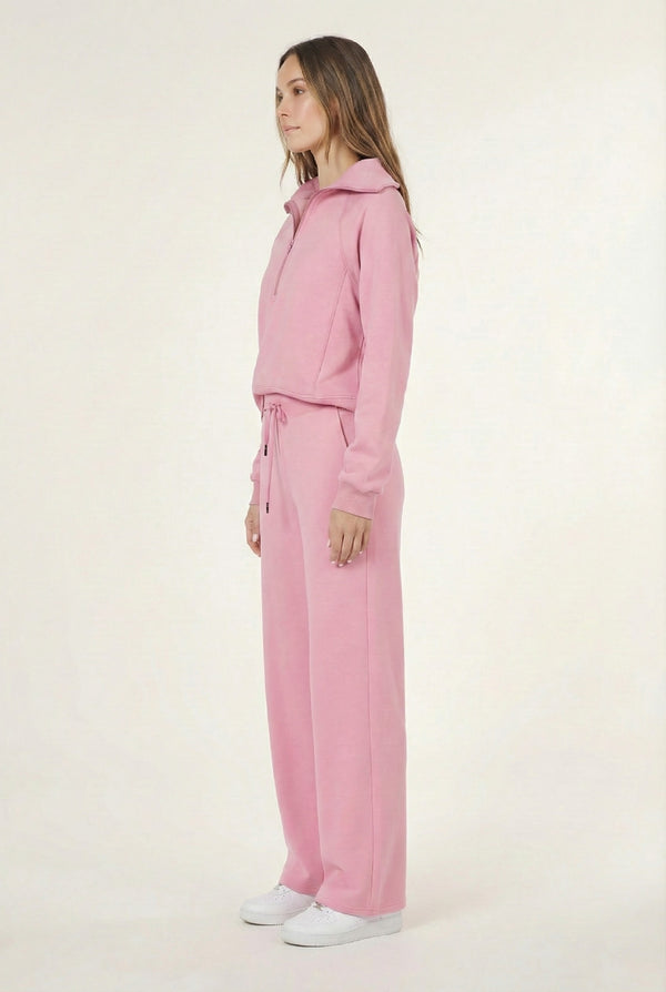 Woman wearing the LOHNR Élan Set in Rose Petal, featuring a smooth, sweatshirt-material half-zip pullover and matching structured pants.