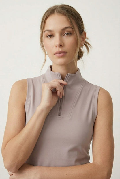 A woman posing in a Stone Veil colored sleeveless sporty dress featuring a zip-up mock neck.