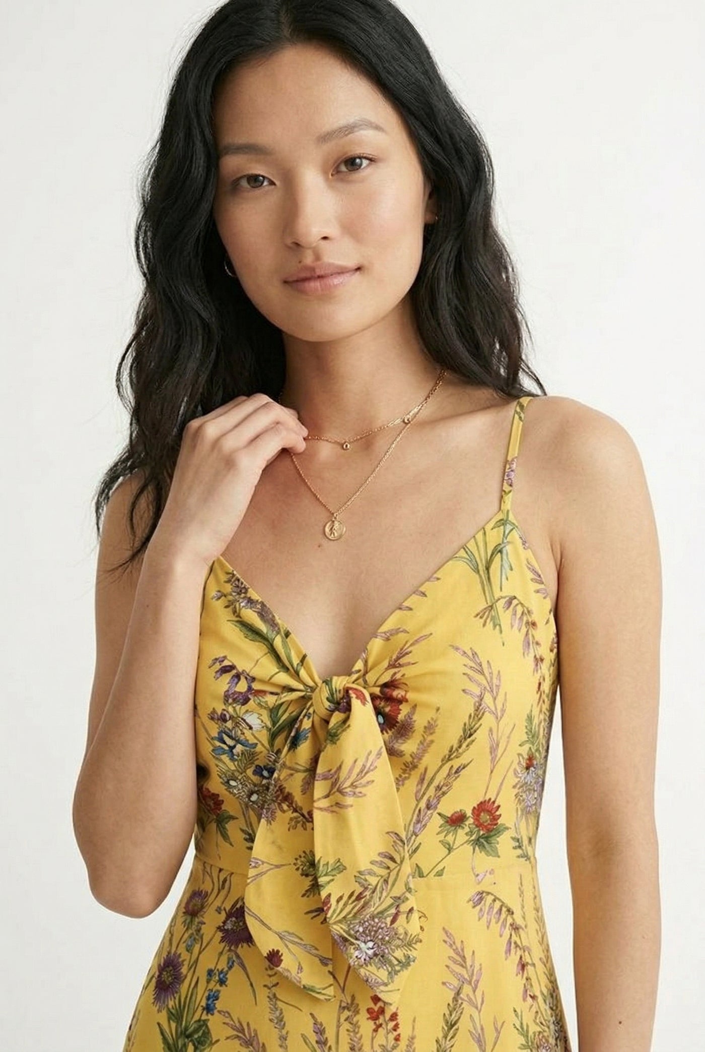 Woman wearing a soft honey yellow floral print maxi dress with spaghetti straps