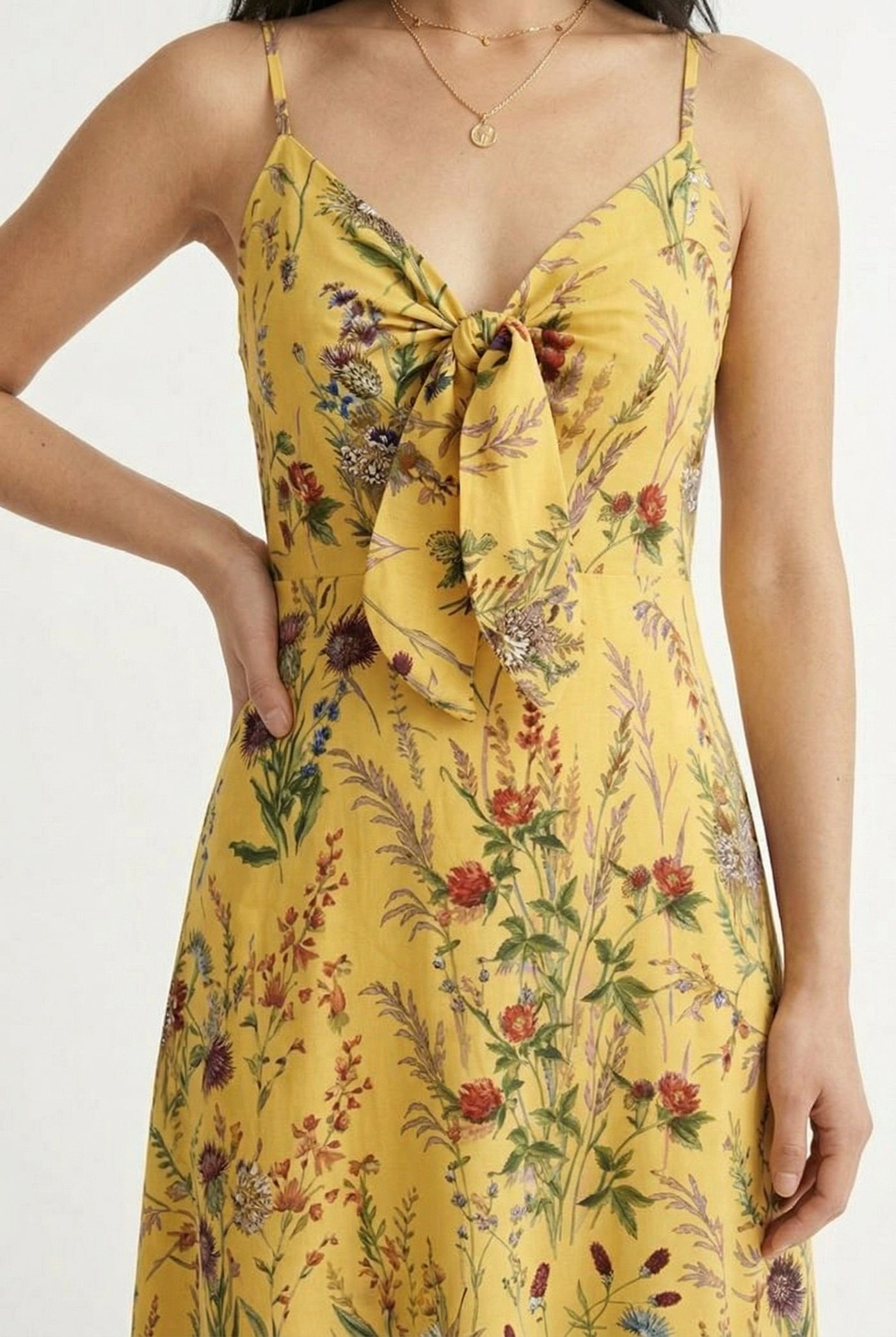 Woman wearing a soft honey yellow floral print maxi dress with spaghetti straps