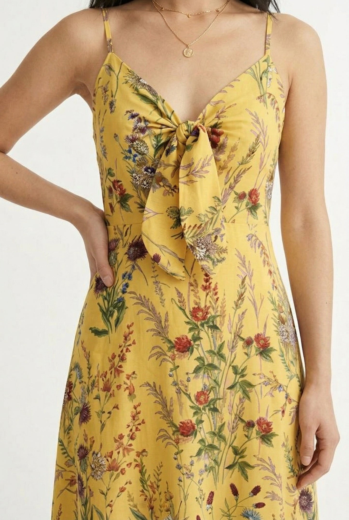 Woman wearing a soft honey yellow floral print maxi dress with spaghetti straps